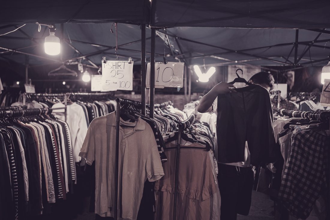 Covered market at night with jackets and shirts on rails