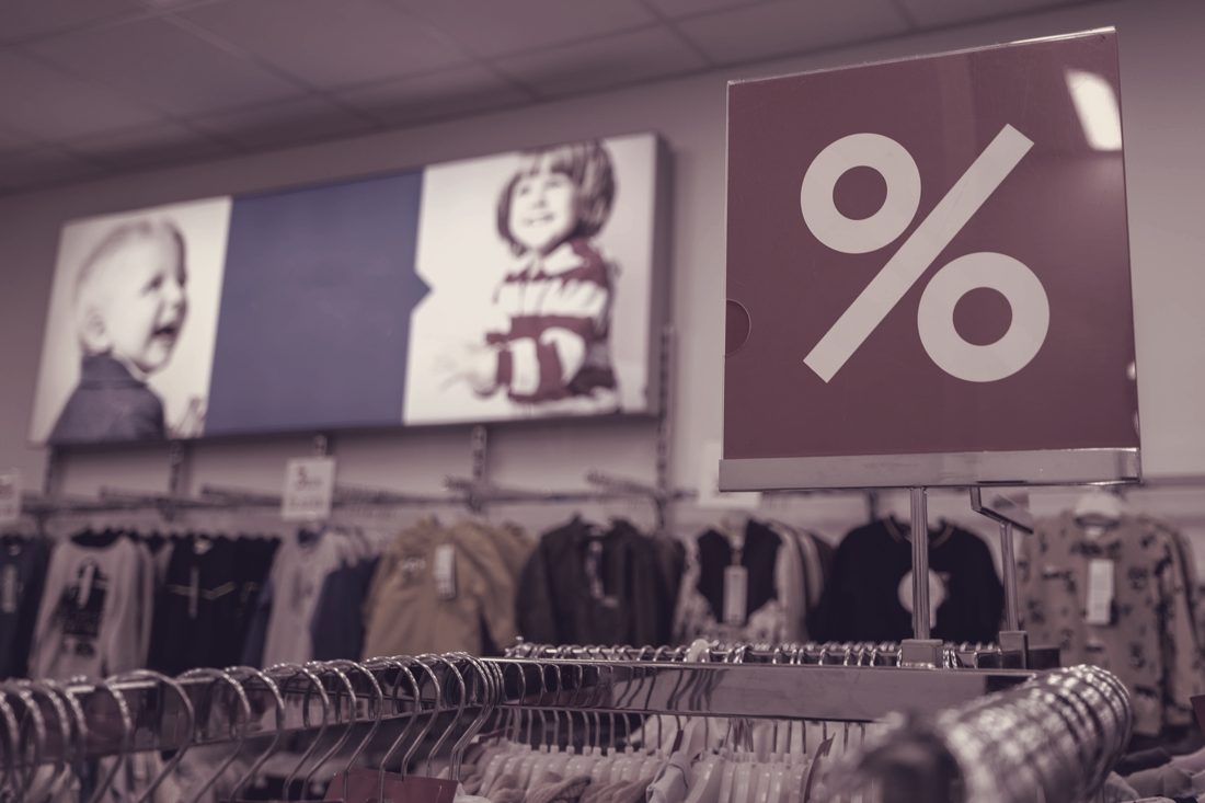 Outlet interior with tops on rails and a percent sign — offprice retail where our lots end up